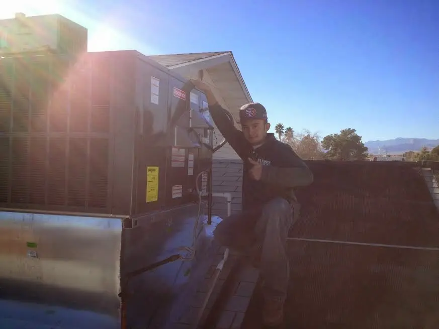 HVAC technician performing Heat Pump Repair on a rooftop unit in Ada